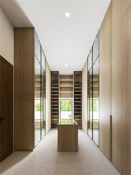 Spacious dressing area featuring light wood-finish cabinetry, integrated shelving, and a central island with a glass top