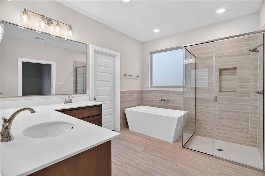 Contemporary bathroom featuring a freestanding tub, a walk-in shower with clear glass enclosure, dual vanity with undermount sinks and quartz countertops, and neutral-toned wall and floor tiling