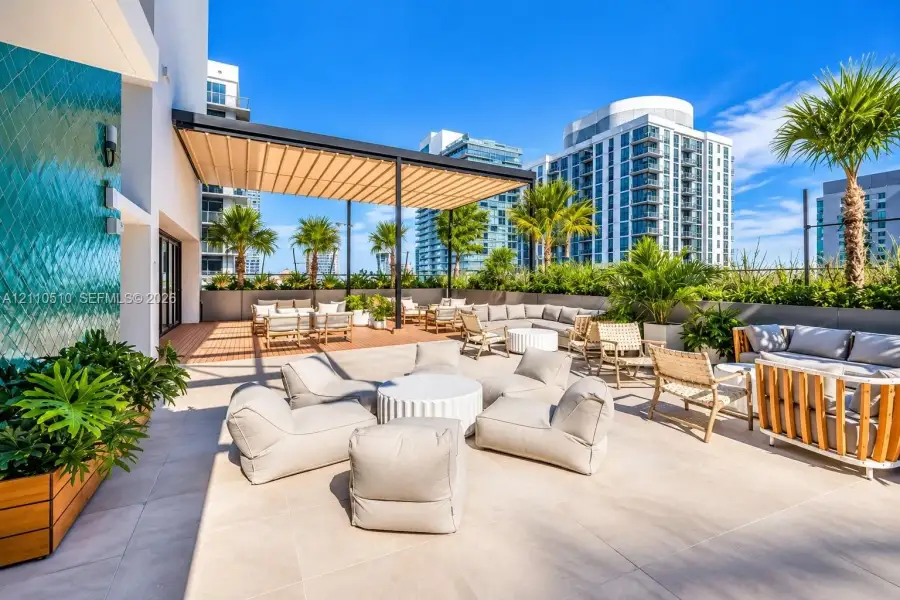 Outdoor terrace featuring large-format tile flooring, a structured pergola, and a decorative textured accent wall Outdoor terrace featuring large-format tile flooring, a structured pergola, and a decorative textured accent wall