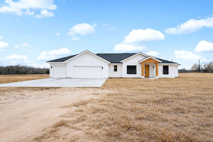 Modern inspired farmhouse featuring concrete driveway, a garage, and a front yard