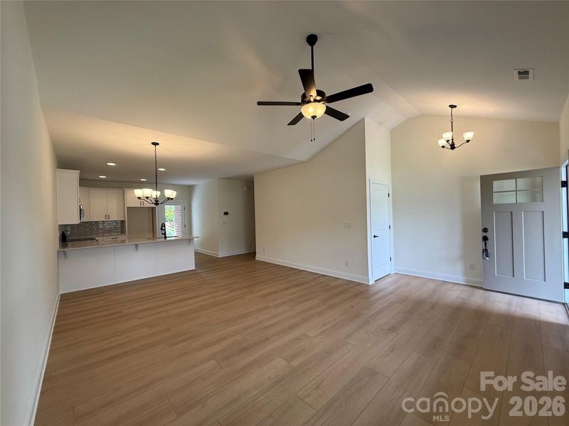 A large family room with vaulted ceiling, luxury vinyl plank floorin and open floor plangreet you upon entry.