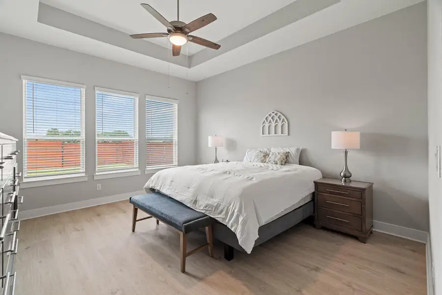 Bedroom with a raised ceiling, light wood-style floors, and ceiling fan Bedroom with a raised ceiling, light wood-style floors, and ceiling fan