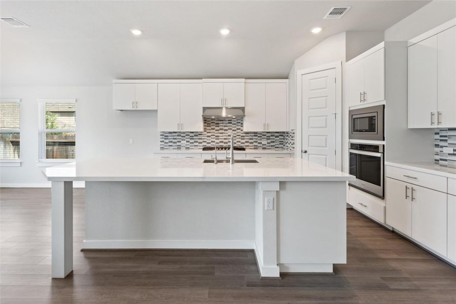 Kitchen with white cabinets, tasteful backsplash, stainless steel appliances, dark wood finished floors, and recessed lighting