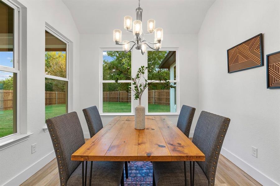 Dining space with an inviting chandelier, light wood-type flooring, and lofted ceiling