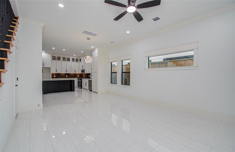 Tall ceilings and recessed lighting with a ceiling fan create a modern open-concept living area.