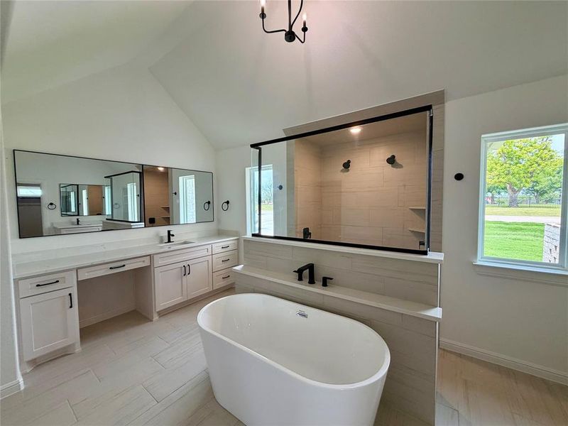 Contemporary bathroom featuring a freestanding soaking tub, a separate glass-enclosed shower, dual vanity with extensive counter space, and light-toned tile flooring