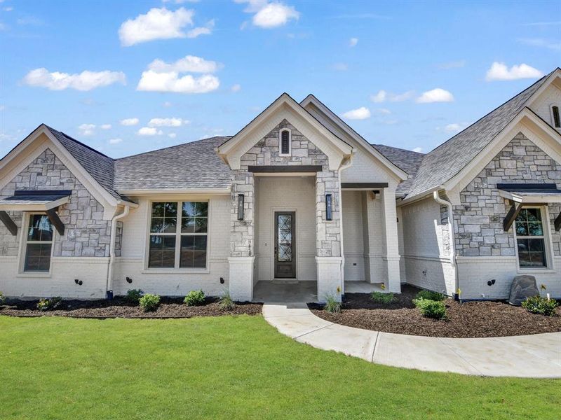 View of front of house with stone siding, a shingled roof, a front lawn, and brick siding View of front of house with stone siding, a shingled roof, a front lawn, and brick siding