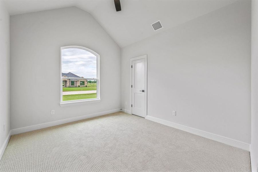 Carpeted spare room with lofted ceiling, ceiling fan, and baseboards