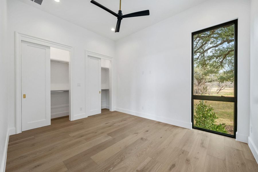 Unfurnished bedroom with two closets, light wood-style flooring, ceiling fan, and recessed lighting