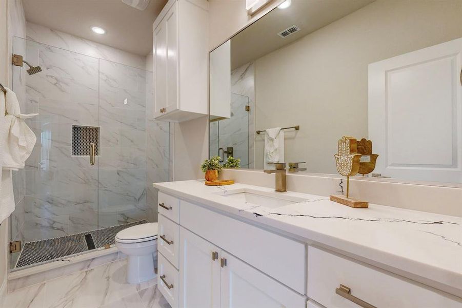 Hall Bathroom featuring vanity with extensive cabinet space, toilet, tile floors, and a shower with door