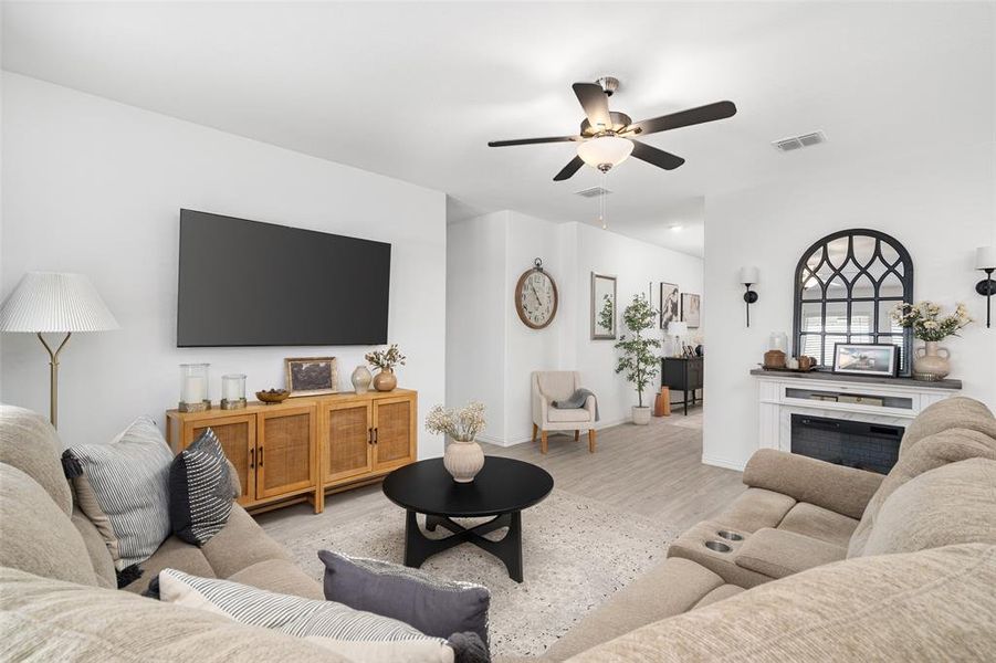 Well-appointed living area featuring a ceiling fan, light-colored flooring, and a decorative fireplace