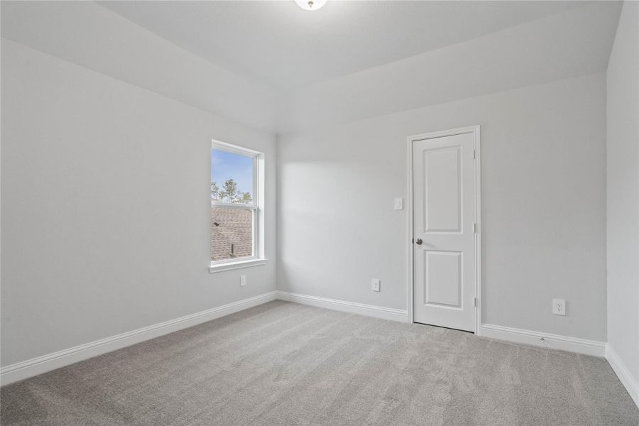 This inviting bedroom also offers neutral walls, plush carpet flooring, and a large window that fills the space with natural light.