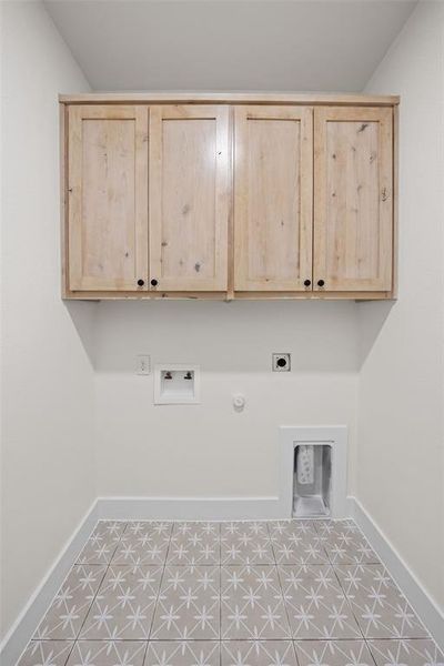 Washroom with gas dryer hookup, hookup for a washing machine, electric dryer hookup, cabinet space, and light tile patterned floors