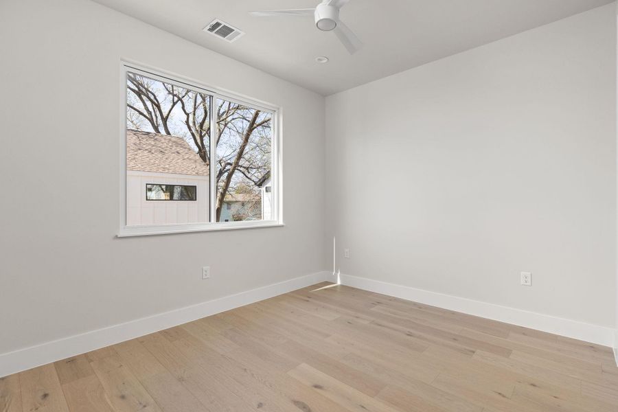 Empty room with visible vents, ceiling fan, baseboards, and light wood-style floors