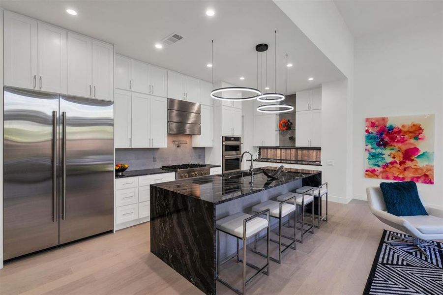 Kitchen featuring white cabinets, a kitchen island with sink, extractor fan, appliances with stainless steel finishes, and light hardwood / wood-style floors