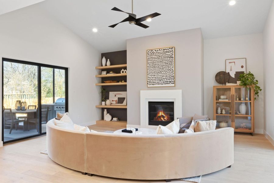 Living area with a glass covered fireplace, a ceiling fan, light wood-style flooring, and recessed lighting