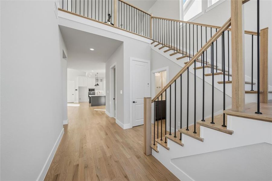 Stairway featuring wood finished floors, a high ceiling, and recessed lighting