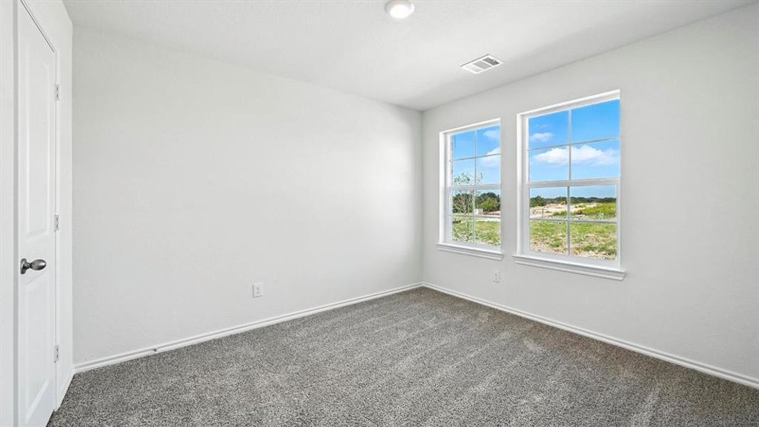 Room featuring two double-hung windows, a white paneled door, gray carpet, white baseboards, and a flush-mount ceiling light