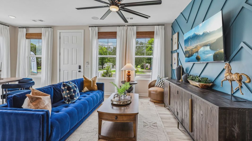 Gathering room with ceiling fan, hard surface flooring, and accent wall