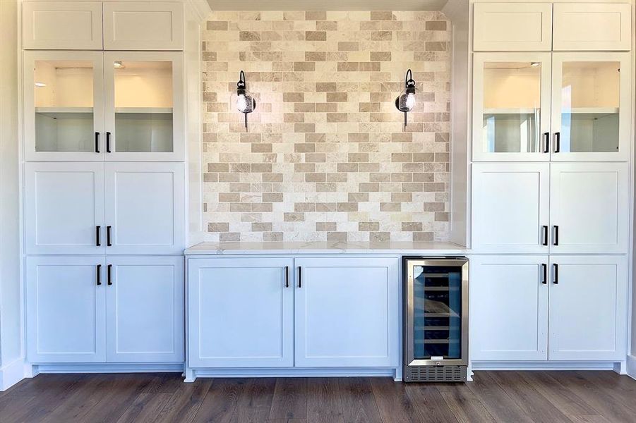 Indoor dry bar with backsplash, glass insert cabinets, beverage cooler, and white cabinets