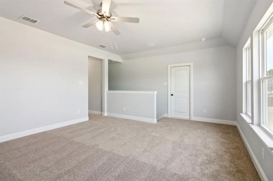 Carpeted empty room with vaulted ceiling and ceiling fan