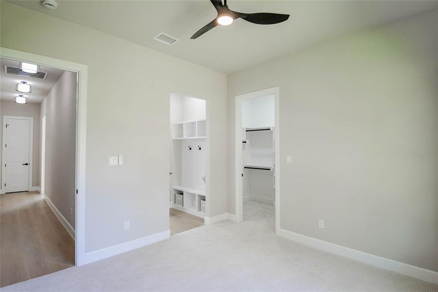 Unfurnished bedroom with light carpet, a spacious closet, connected bathroom, and a ceiling fan Unfurnished bedroom with light carpet, a spacious closet, connected bathroom, and a ceiling fan