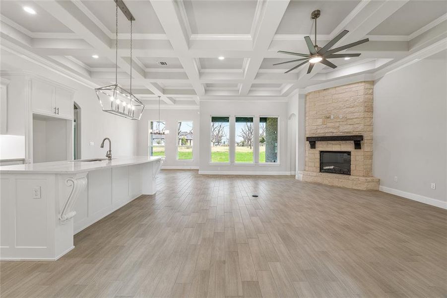 Unfurnished living room with light wood-type flooring, a fireplace, beamed ceiling, recessed lighting, and a ceiling fan