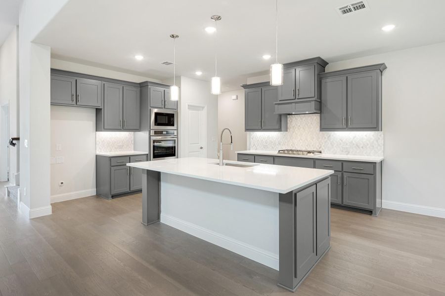 Kitchen with gray cabinets, large center island, white countertops, and hardwood floors Kitchen with gray cabinets, large center island, white countertops, and hardwood floors