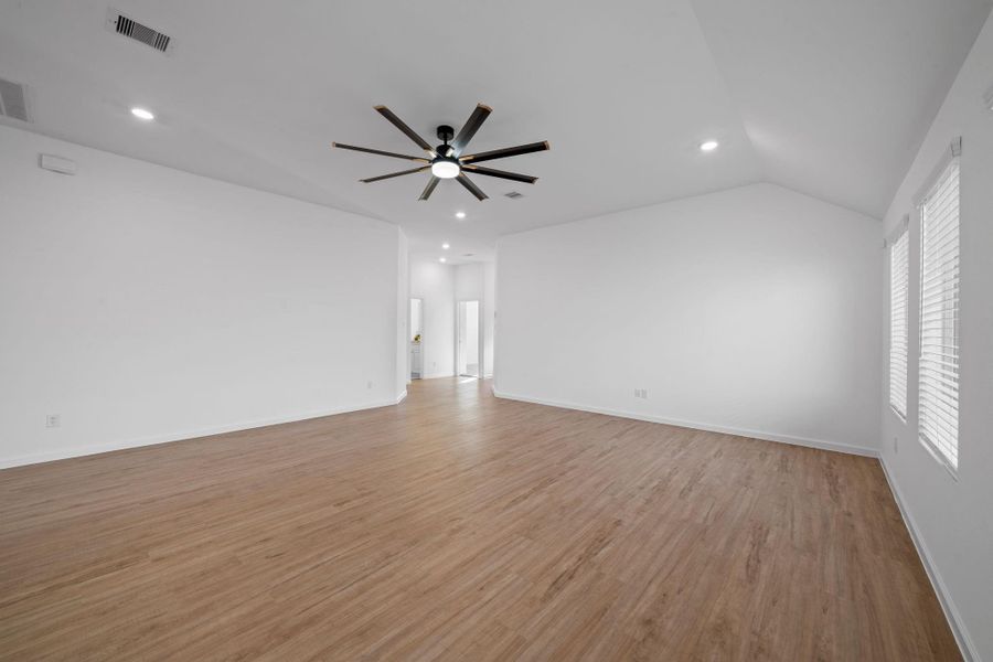 The soaring ceilings and recessed lighting give the room an airy, modern feel, while the warm wood-style flooring keeps everything inviting and comfortable.