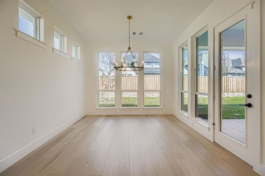 Unfurnished dining area with light wood-style flooring and a chandelier Unfurnished dining area with light wood-style flooring and a chandelier