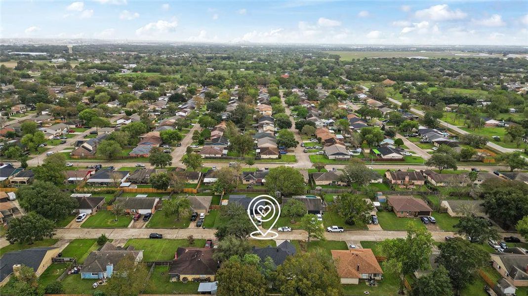 This aerial photo showcases a large suburban neighborhood with single-family homes, spacious yards, and tree-lined streets, with an open landscape in the distance.