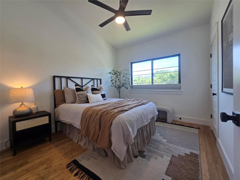 High vaulted ceilings and rich wood floors anchor this comfortable modern bedroom setup.
