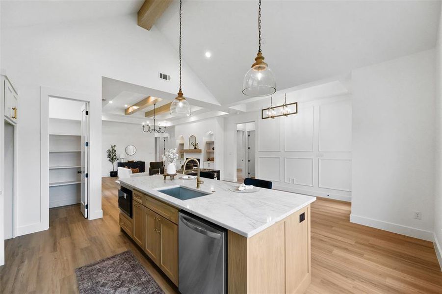 Kitchen island featuring a substantial countertop, integrated sink, and stainless steel dishwasher
