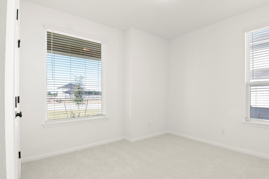 Empty room with light colored carpet and baseboards