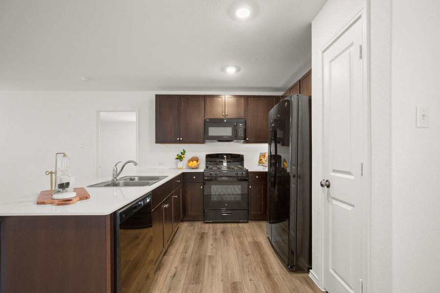 The kitchen opens to the living and dining areas, perfect for everyday living and entertaining, and features quartz countertops, a casual peninsula, and a pantry.