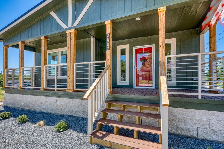 A welcoming red door opens onto a spacious front porch, detailed with sleek horizontal railings. A welcoming red door opens onto a spacious front porch, detailed with sleek horizontal railings.