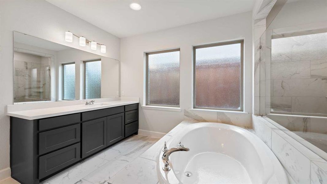 Bathroom featuring shower with separate bathtub, vanity, and plenty of natural light