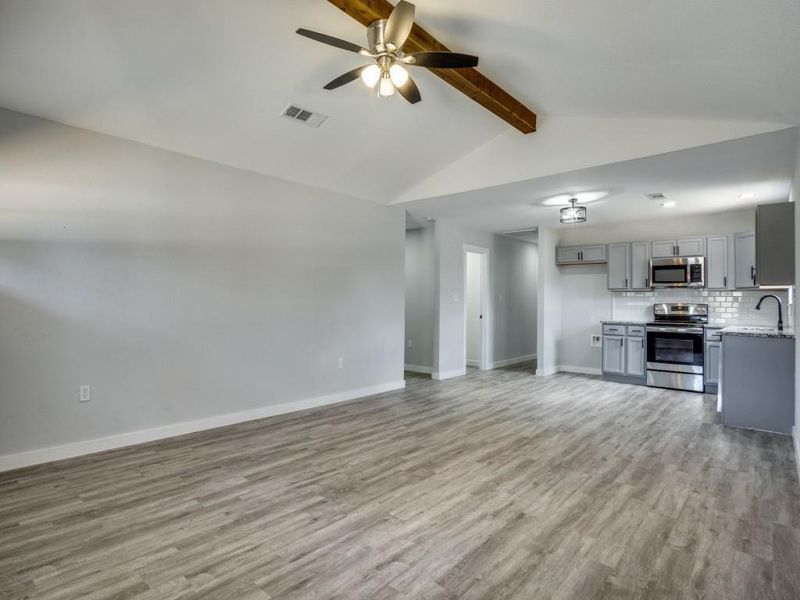 Unfurnished living room with lofted ceiling with beams, sink, ceiling fan, and light hardwood / wood-style floors Unfurnished living room with lofted ceiling with beams, sink, ceiling fan, and light hardwood / wood-style floors