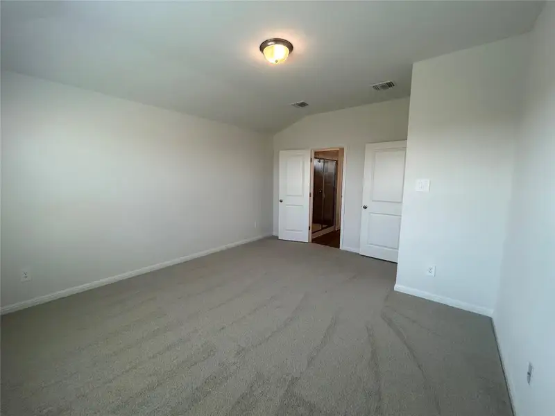 Unfurnished bedroom with carpet flooring and vaulted ceiling Unfurnished bedroom with carpet flooring and vaulted ceiling