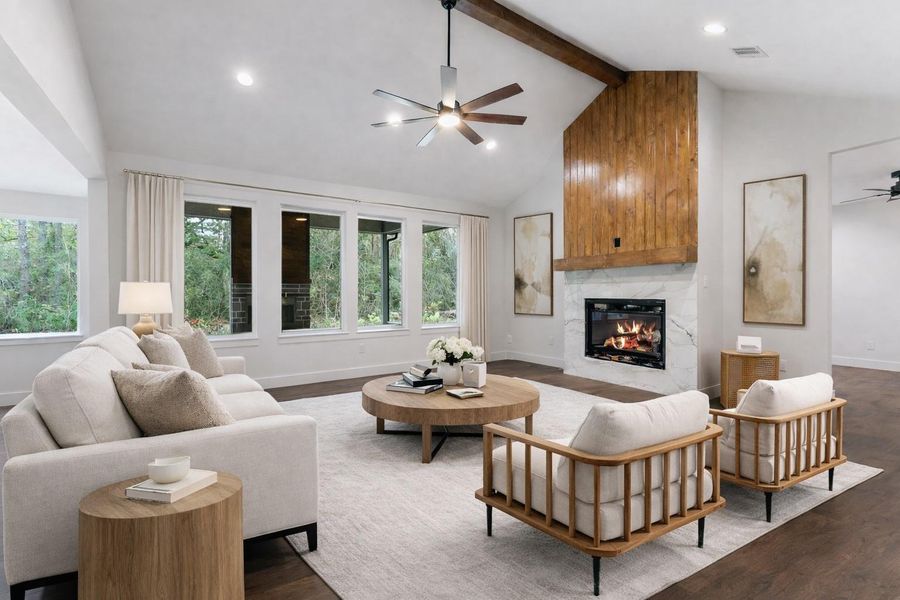 Experience the warmth and elegance of this digitally staged living room, featuring a cozy fireplace, stylish wood accents, and abundant natural light through expansive windows, perfect for relaxation and entertaining.