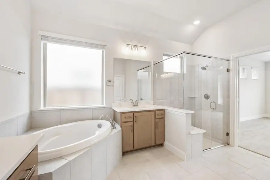 Master bathroom with soaking tub, glass walk-in shower, and wood vanity with white countertop