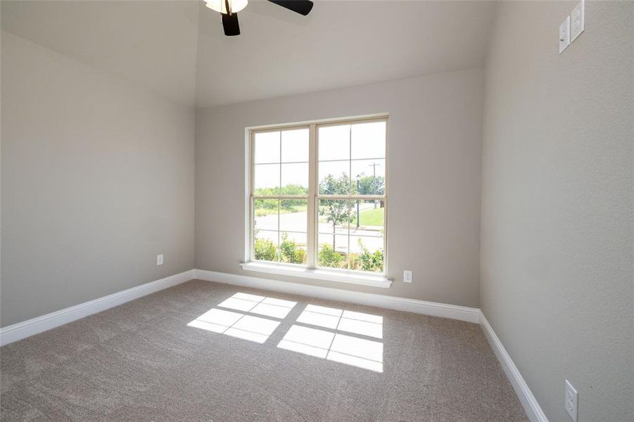 Carpeted spare room with vaulted ceiling and ceiling fan