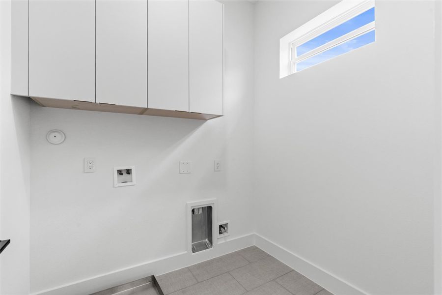 Utility, elevated: a dedicated laundry room with floor tile underfoot, fitted upper cabinetry for concealed storage, and smart hookups for both gas and electric. A high window washes the space in daylight while maintaining privacy, turning everyday tasks into a clean, well-composed ritual. Utility, elevated: a dedicated laundry room with floor tile underfoot, fitted upper cabinetry for concealed storage, and smart hookups for both gas and electric. A high window washes the space in daylight while maintaining privacy, turning everyday tasks into a clean, well-composed ritual.