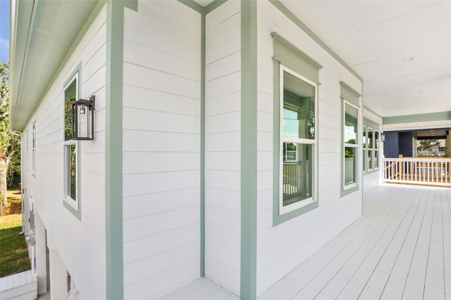 Charming porch with crisp white siding and soft green trim, offering space for relaxation and outdoor enjoyment.
