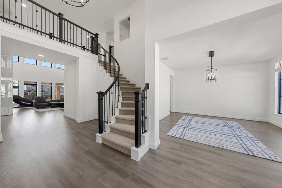 Entrance foyer with a chandelier, wood finished floors, a towering ceiling, baseboards, and stairway