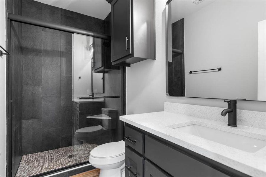 Bathroom with vanity, toilet, and an enclosed shower