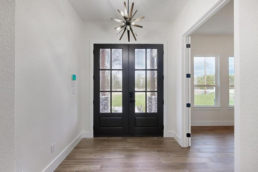 Entryway featuring wood tiled floors, french doors, and a textured wall Entryway featuring wood tiled floors, french doors, and a textured wall