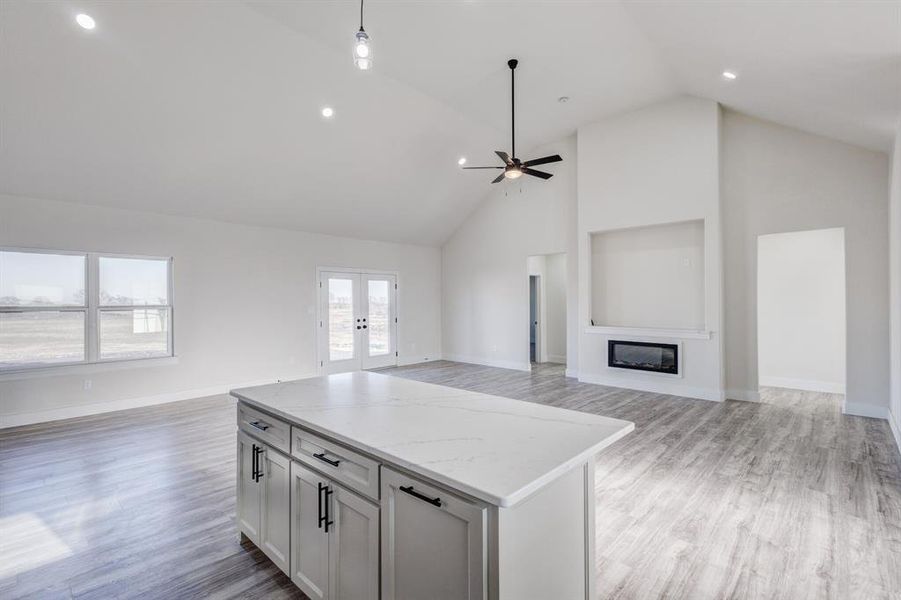 Kitchen with light stone countertops, a center island, ceiling fan, hanging light fixtures, and light wood-type flooring