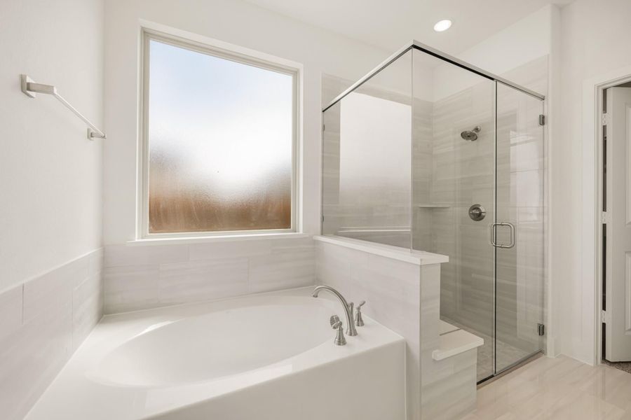 Bathroom with soaking tub, glass-enclosed shower, gray tile walls, and frosted window