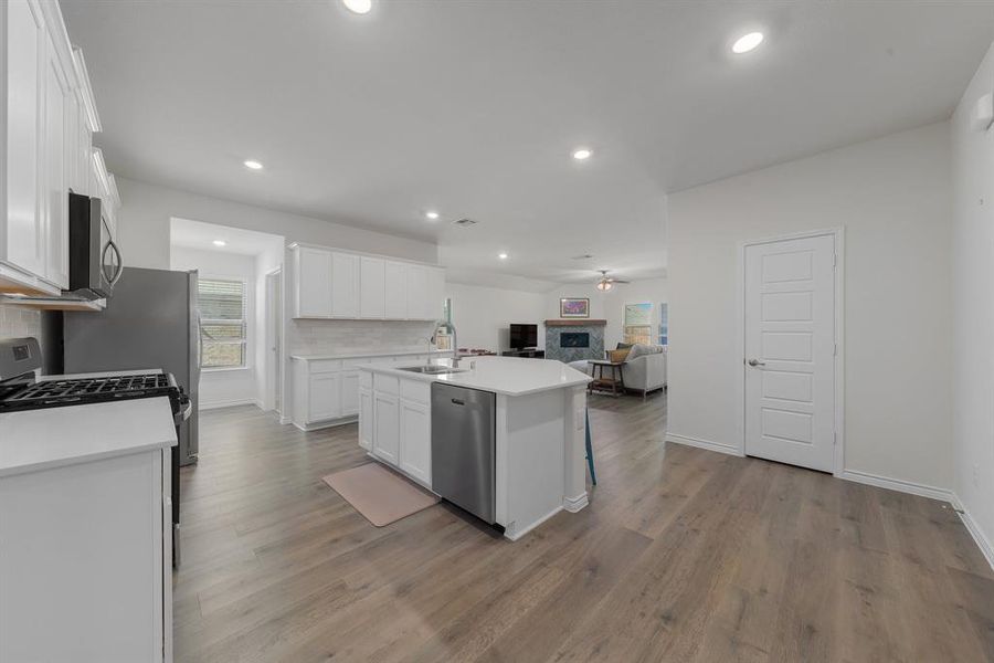 Kitchen featuring stainless steel appliances, a sink, white cabinetry, open floor plan, and decorative backsplash